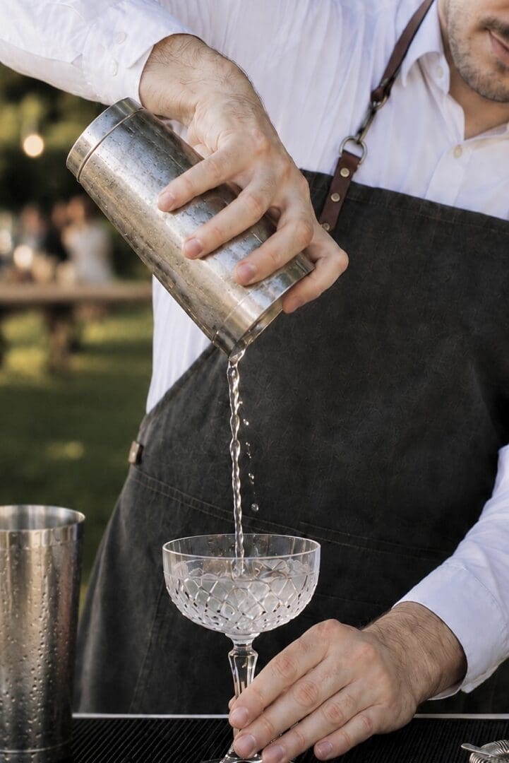 Bartender pouring cocktail into crystal coupe glass