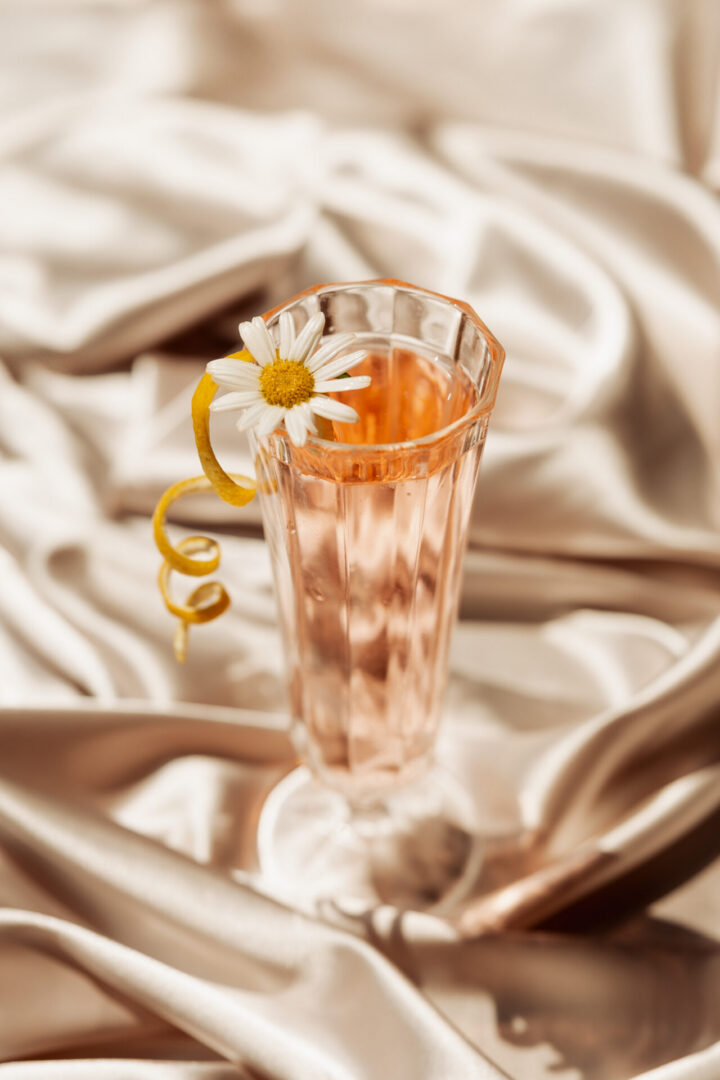 Pink cocktail with daisy and lemon twist